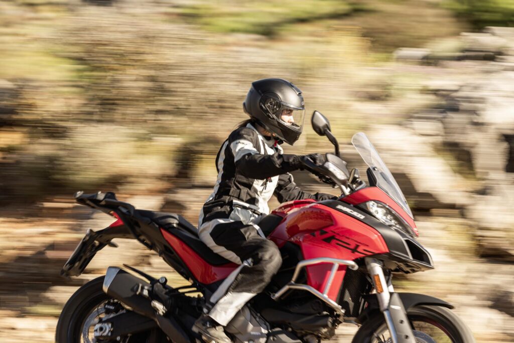 The Cardo BEYOND GTS carbon fiber smart helmet shown outdoors in an adventure riding setting.